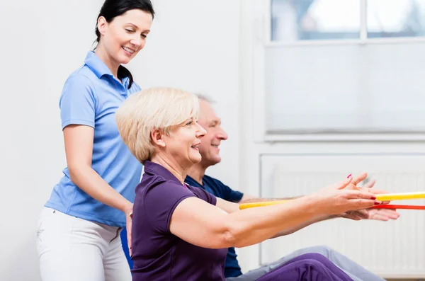 Senior couple in physiotherapy doing exercise with hula hoop — Stock Photo, Image