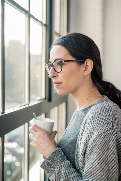 Young pensive woman looking through the window during break — Stock Photo, Image