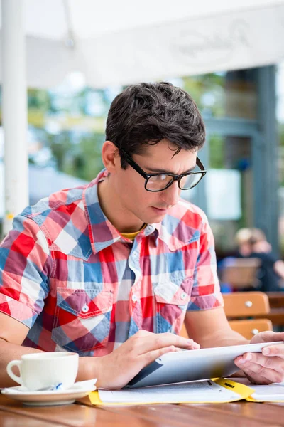 Man drinking coffee in street cafe reading on tablet device — Stock Photo, Image