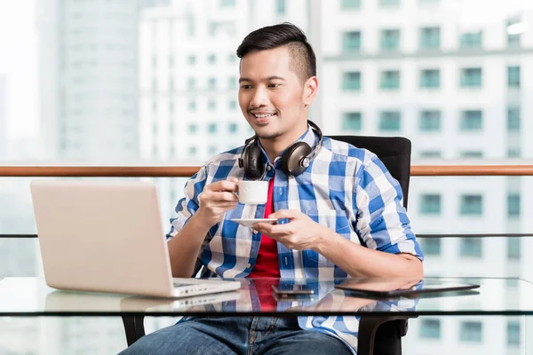 Indonesischer Profi beim Kaffeetrinken am Laptop — Stockfoto