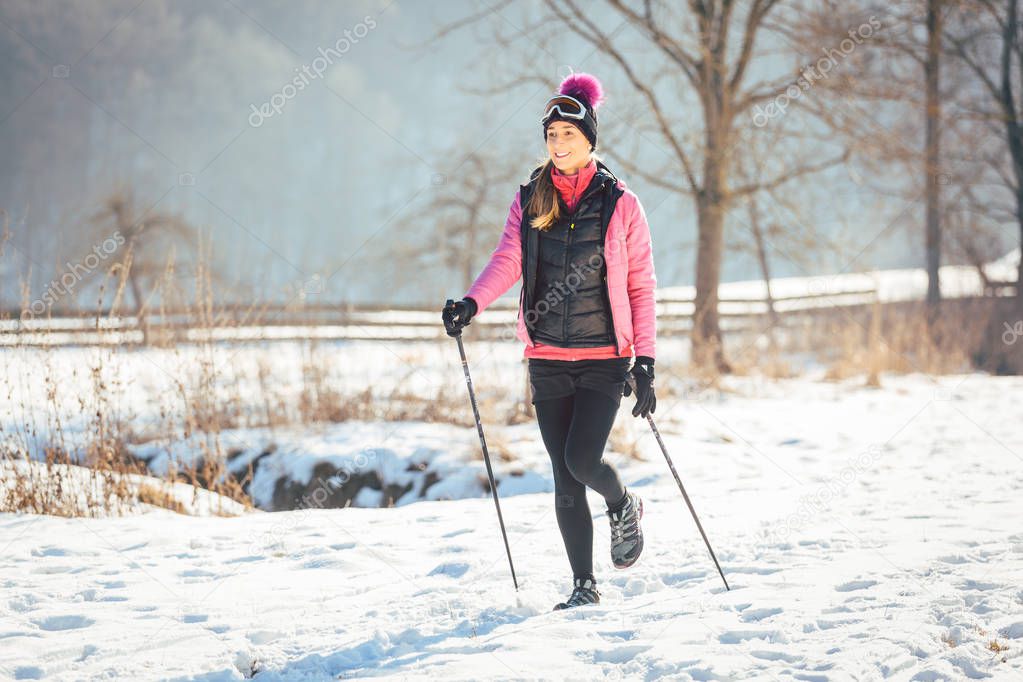 Fit woman Nordic walking in winter landscape