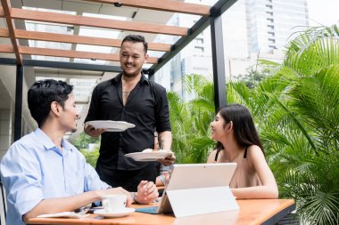 Neşeli garson genç bir çift tablo için iki tabak yiyecek getiren