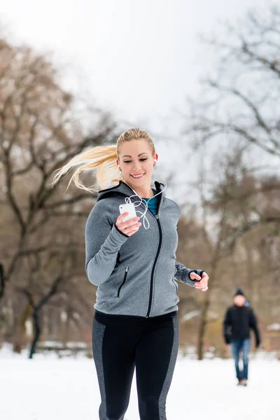 Mujer corriendo por un camino en el día de invierno en el parque — Foto de Stock