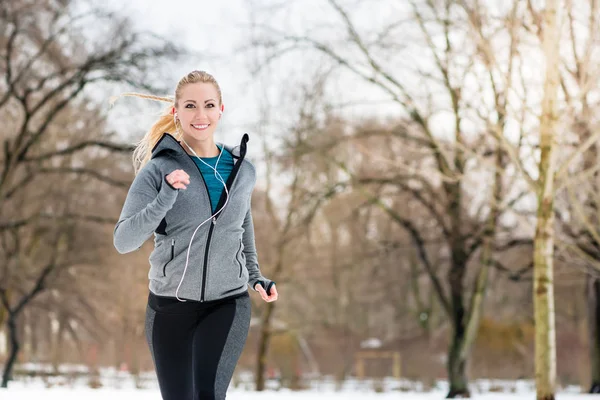 公園で冬の日の道を走っている女性 — ストック写真