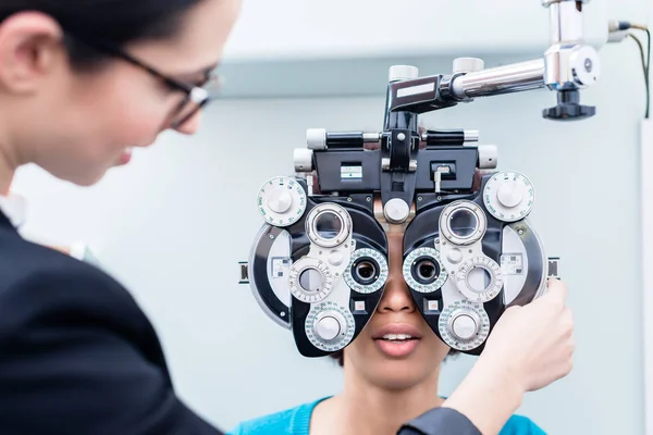 Opticida e mulher ao exame oftalmológico com phoropter — Fotografia de Stock