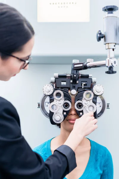 Ottico e donna all'esame oculare con phoropter — Foto Stock