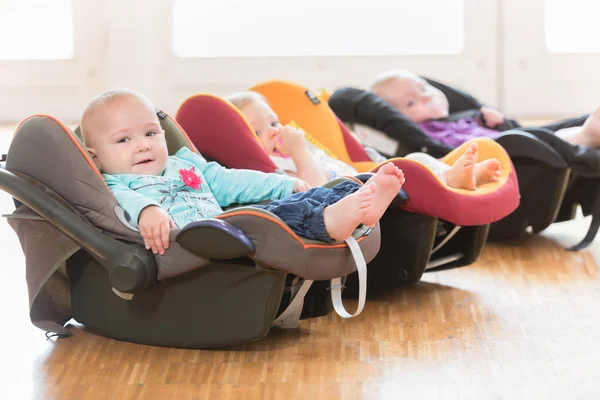 bébé fille de 4 mois assis dans un siège pour bébé avec des jouets regarder  à côté du jouet Photo Stock - Alamy