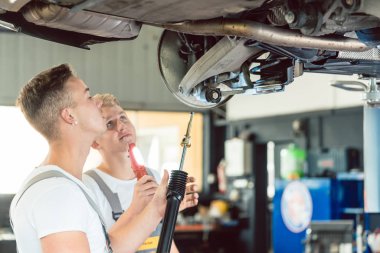 Yetenekli otomatik mekanik, birlikte modern otomobil tamir dükkanında çalışırken amortisörler kaldırdı arabanın yerine yan görünüm