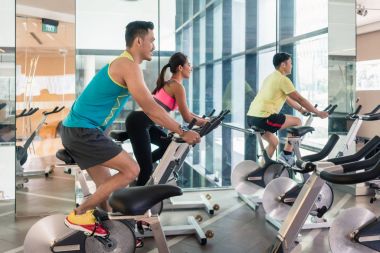 yakışıklı ve kendine güvenen genç adam HIIT kapalı bisiklet grup sınıf sırasında