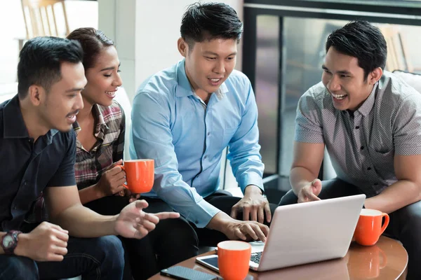 Dos jóvenes alegres usando un ordenador portátil mientras comparten ideas de negocios — Foto de Stock