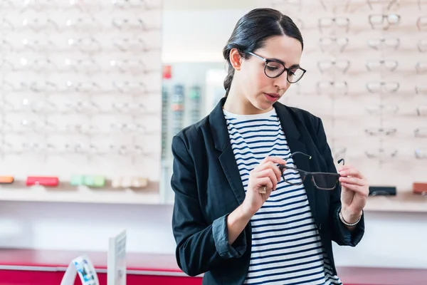 Woman choosing glasses in optician shop