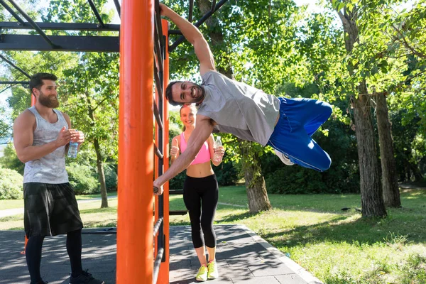 Starker junger Mann, der mit gebeugten Beinen eine Übung mit menschlicher Flagge praktiziert — Stockfoto