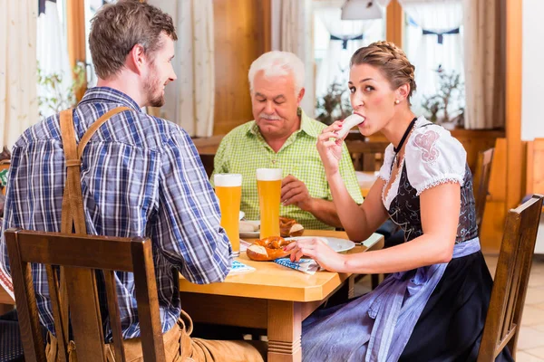 男性と女性のババリア地方のレストランでソーセージを食べる — ストック写真