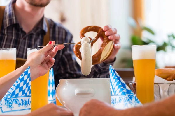 Cropped view of people group eating veal sausages in bavarian restaurant