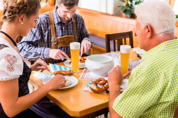 男性と女性のババリア地方のレストランでソーセージを食べる — ストック写真