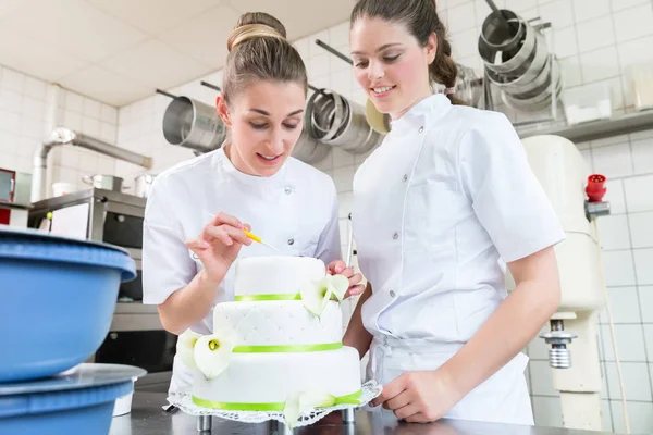 Dos panaderos de pastelería decorando pastel grande — Foto de Stock