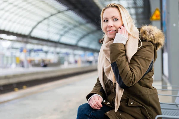 在站台上等待火车的女人用她的电话 — 图库照片