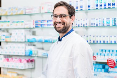 Male pharmacist smiling in pharmacy shop clipart