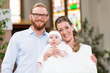 Genç anne ve bebek giyen vaftiz elbisesi ile kilise 