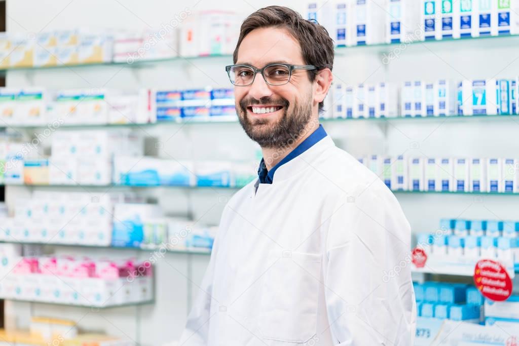 Male pharmacist smiling in pharmacy shop