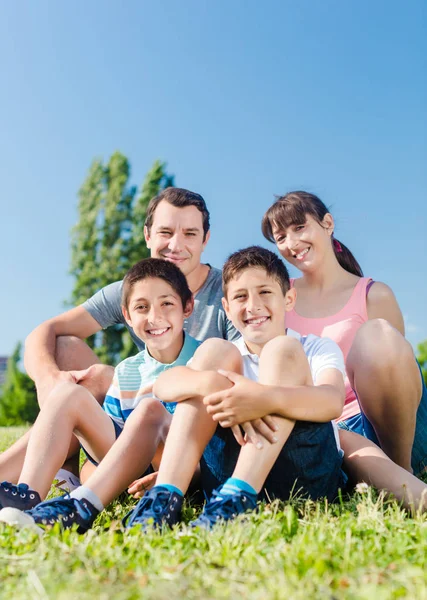 Happy family sitting on meadow — Stock Photo, Image