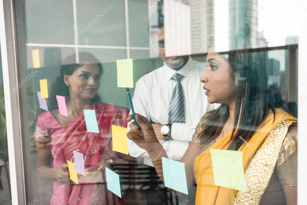 employees sticking reminders on glass wall