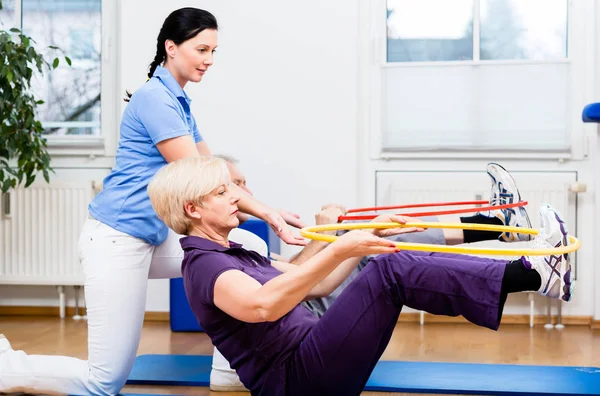 Senior couple in physiotherapy doing exercise with hula hoop — Stock Photo, Image