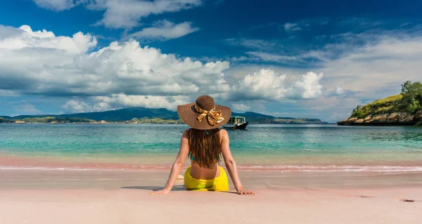 Młoda kobieta siedzi na piasek na plaży Pink Komodo Island, — Zdjęcie stockowe