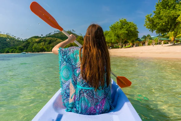 Mujer joven remando en una canoa a lo largo de la orilla de un islán idílico — Foto de Stock