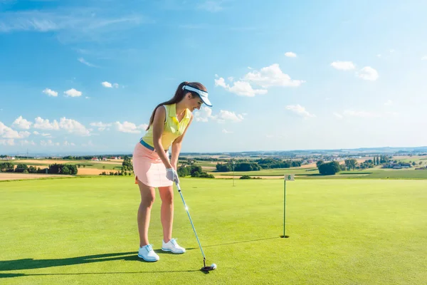 Comprimento total de uma mulher atraente segurando um clube de golfe antes de bater a bola — Fotografia de Stock