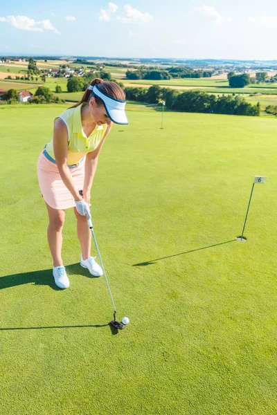 Полная длина привлекательной женщины, держащей клюшку для гольфа, прежде чем ударить по мячу — стоковое фото
