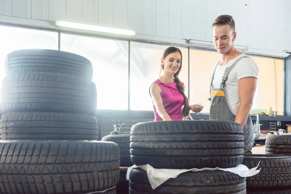 Schöner Automechaniker, der einem Kunden hilft, aus verschiedenen Reifen auszuwählen — Stockfoto