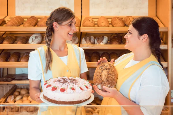 Verkäuferinnen in Bäckerei mit Kuchen und Brot — Stockfoto