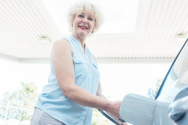 Close-up of the hand of a senior female driver holding the gas dispenser — Stock Photo, Image