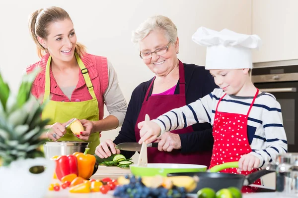 Mamie, maman et fils parlent en cuisinant dans la cuisine — Photo