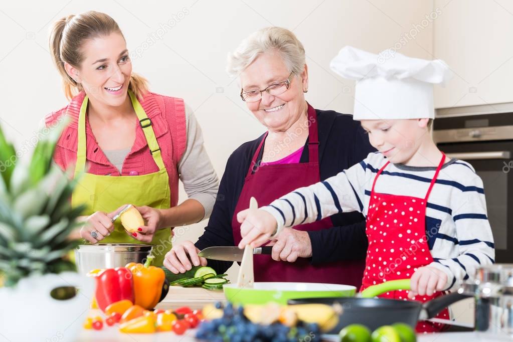 Granny, mum and son talking while cooking in kitchen