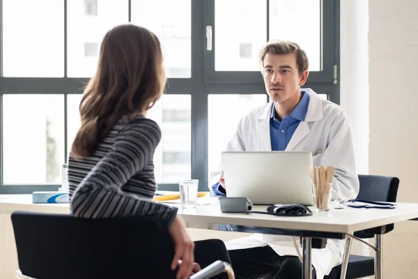 Junger Arzt hört seinem Patienten mit Respekt und Hingabe zu — Stockfoto