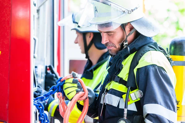 Fire fighter kontrollera slangarna på brandbil — Stockfoto