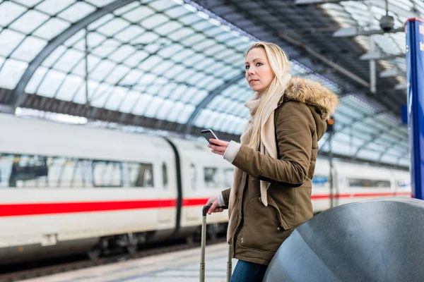 Frau im Bahnhof nutzt Fahrplan-App am Telefon — Stockfoto