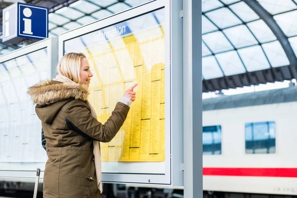 Mulher leitura tabela de tempo na estação de trem — Fotografia de Stock