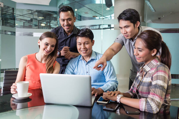 Multi-ethnic team of employees watching a funny video or presentation