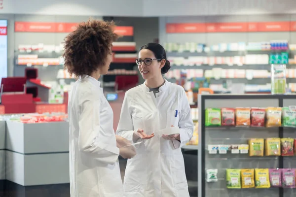 Deux collègues sympathiques parlent tout en travaillant ensemble dans une pharmacie moderne — Photo