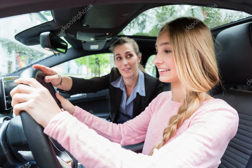 Student on wheel of car in driving lesson with her teacher