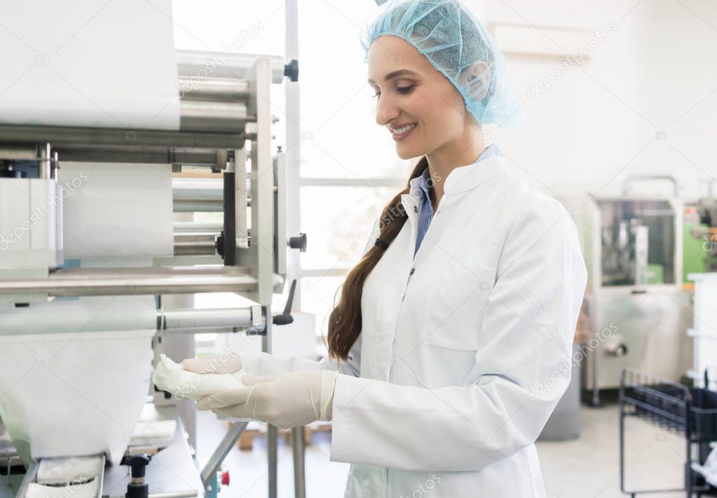 Happy employee wearing lab coat while handling sterile wipes