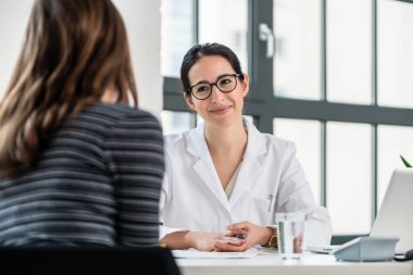 Kadın doktor hastasını tıbbi merkezinde otururken Danışma sırasında dinleme