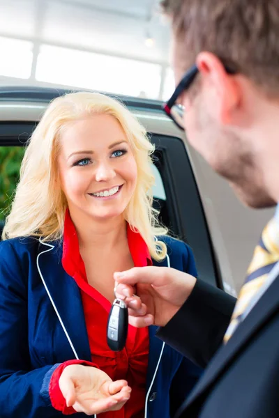 Frau mit Schlüssel zu Neuwagen im Autohaus — Stockfoto