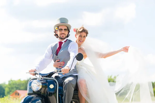 Свадебная пара за рулем мотороллера в платье и костюме — стоковое фото
