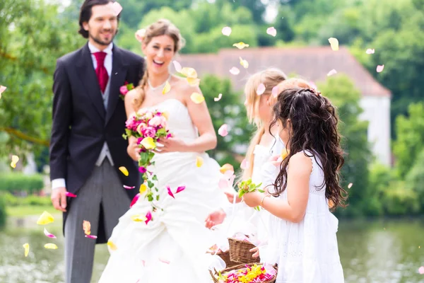 Свадебная пара и подружка невесты, принимающие душ цветы — стоковое фото