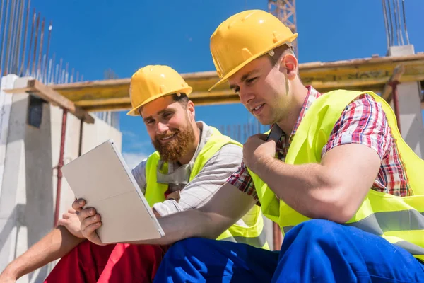 Zwei Arbeiter, die Online-Informationen lesen oder sich ein Video ansehen — Stockfoto