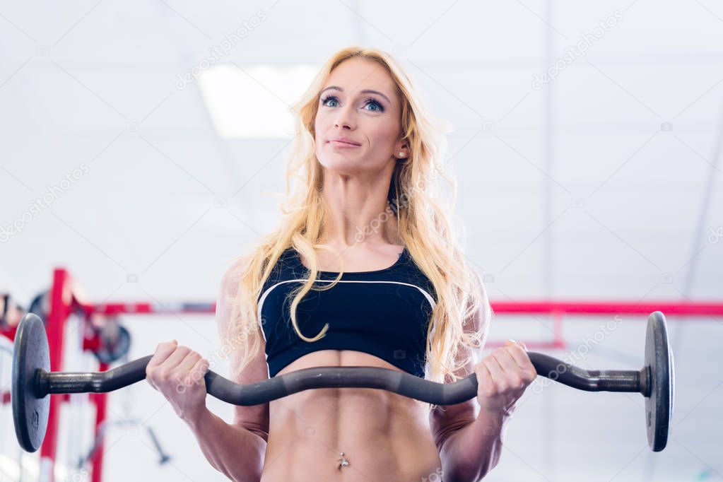 Woman with barbell doing sport in fitness gym